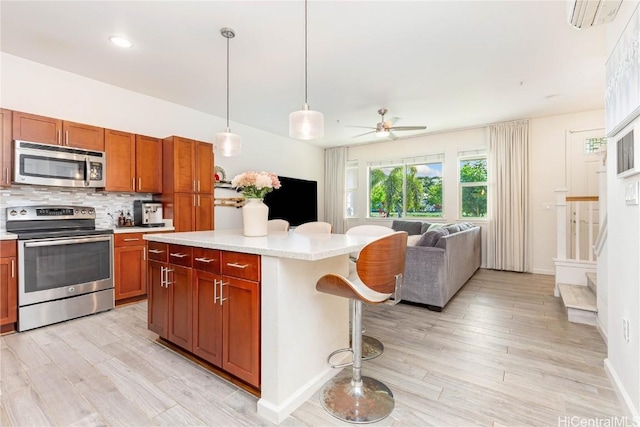 kitchen featuring tasteful backsplash, appliances with stainless steel finishes, open floor plan, a wall mounted air conditioner, and light countertops