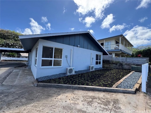 view of side of home with a carport, ac unit, and board and batten siding