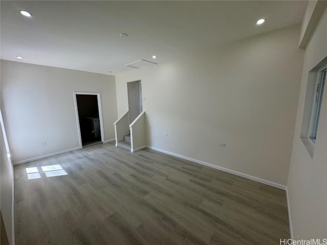 empty room featuring stairs, recessed lighting, baseboards, and wood finished floors