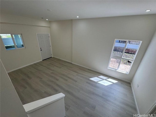 empty room with baseboards, wood finished floors, and recessed lighting