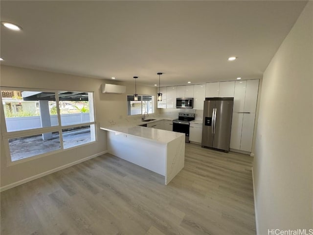 kitchen with decorative light fixtures, stainless steel appliances, white cabinetry, a wall mounted air conditioner, and a peninsula