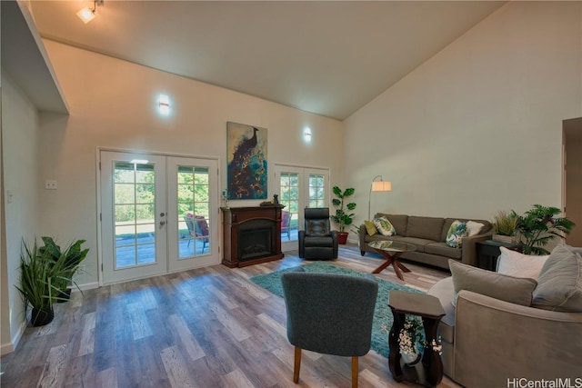 living room featuring high vaulted ceiling, french doors, a fireplace, and wood finished floors