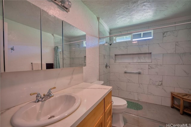 bathroom with tiled shower, toilet, ornamental molding, a textured ceiling, and vanity