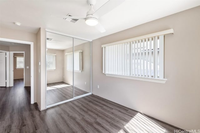 unfurnished bedroom with ceiling fan, a closet, wood finished floors, and visible vents