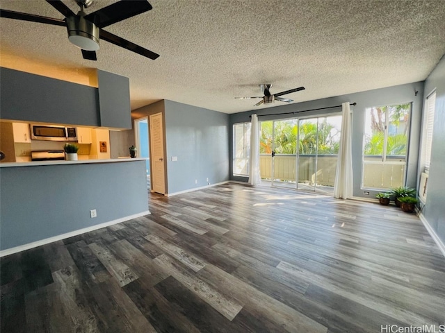 unfurnished living room with dark wood-type flooring, plenty of natural light, and a ceiling fan