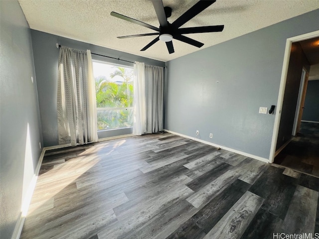 spare room with a textured ceiling, wood finished floors, a ceiling fan, and baseboards