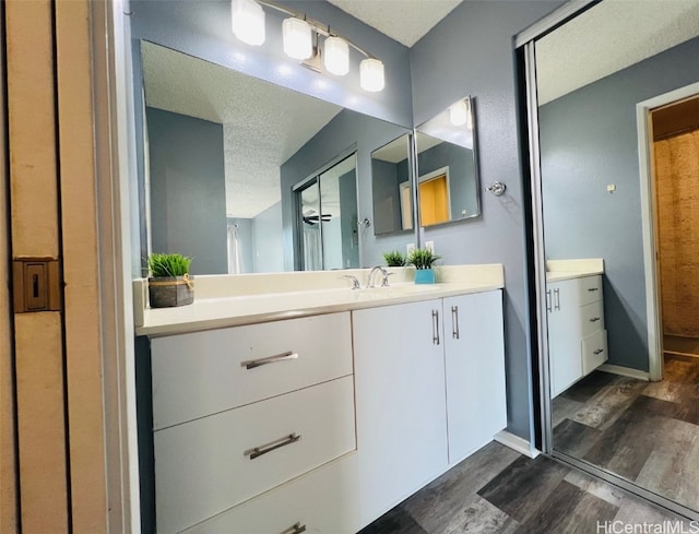 bathroom featuring a textured ceiling, vanity, baseboards, and wood finished floors