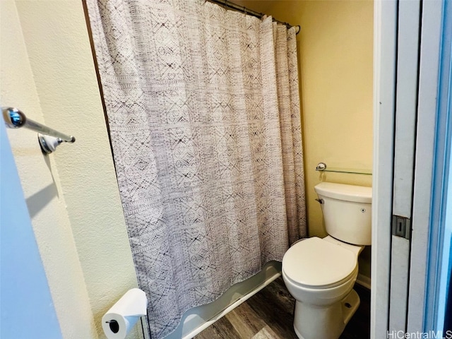 full bathroom featuring a shower with curtain, toilet, and wood finished floors