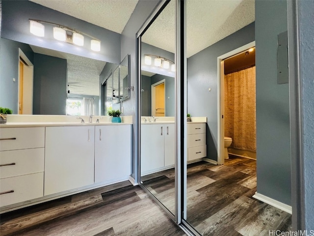 full bathroom featuring a textured ceiling, toilet, wood finished floors, and vanity