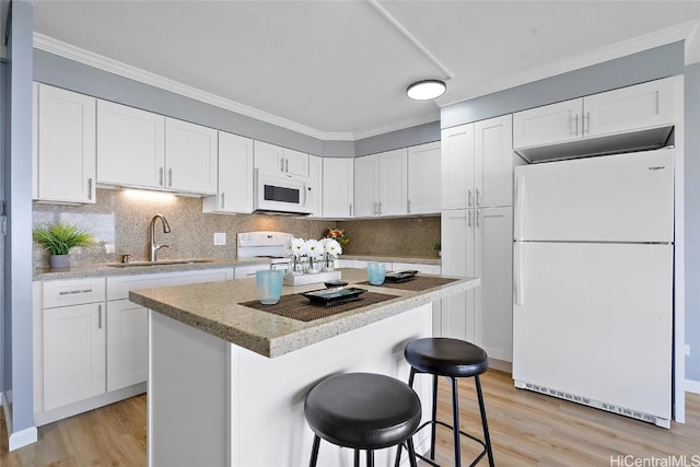 kitchen featuring white appliances, light wood-type flooring, a sink, and white cabinets