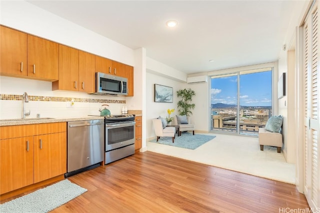 kitchen with light wood finished floors, stainless steel appliances, light countertops, backsplash, and a sink