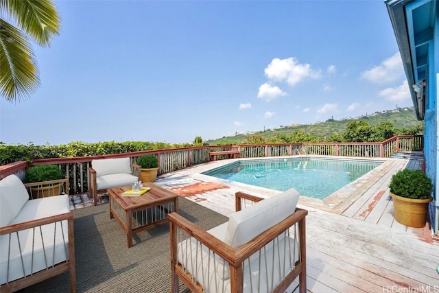 view of pool featuring a deck, a fenced in pool, and an outdoor living space