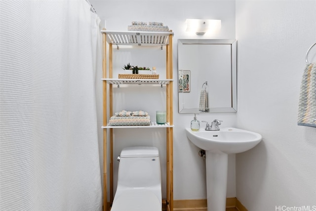 bathroom with curtained shower, a sink, and toilet