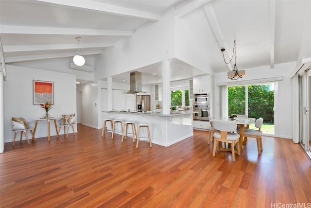 kitchen with appliances with stainless steel finishes, a breakfast bar area, white cabinetry, and island range hood