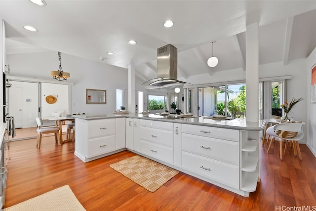 kitchen with pendant lighting, vaulted ceiling with beams, light wood finished floors, white cabinets, and island range hood