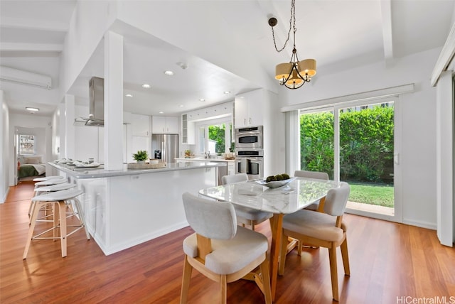 dining area with a chandelier, recessed lighting, a wall unit AC, and light wood-style floors