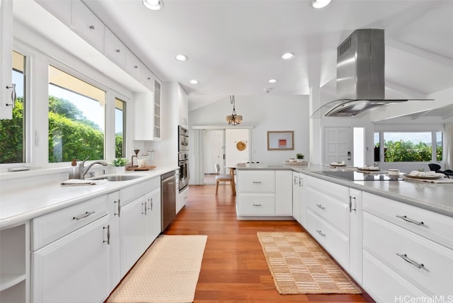 kitchen featuring island range hood, a sink, light wood-style floors, vaulted ceiling, and stainless steel dishwasher