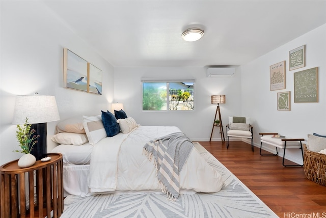 bedroom featuring wood finished floors, baseboards, and a wall mounted AC