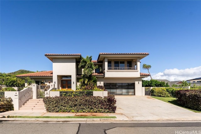 view of front facade featuring driveway, fence, a balcony, and stucco siding