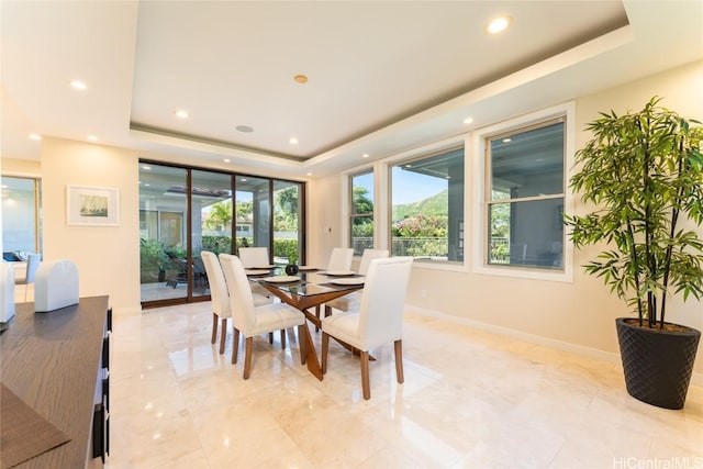dining room with recessed lighting, a raised ceiling, and baseboards