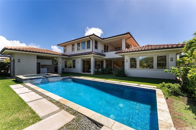 back of property with a balcony, a tile roof, a yard, a pool with connected hot tub, and stucco siding