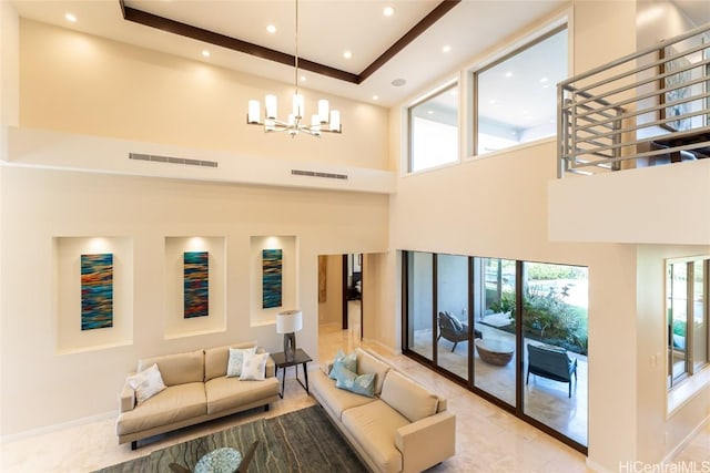 living room with a wealth of natural light, visible vents, a notable chandelier, and a towering ceiling
