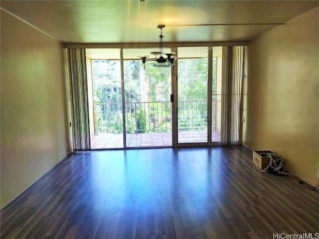 empty room featuring dark wood-type flooring, an inviting chandelier, and expansive windows