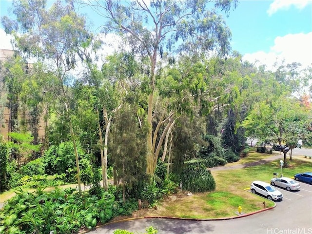 view of home's community with uncovered parking and a lawn