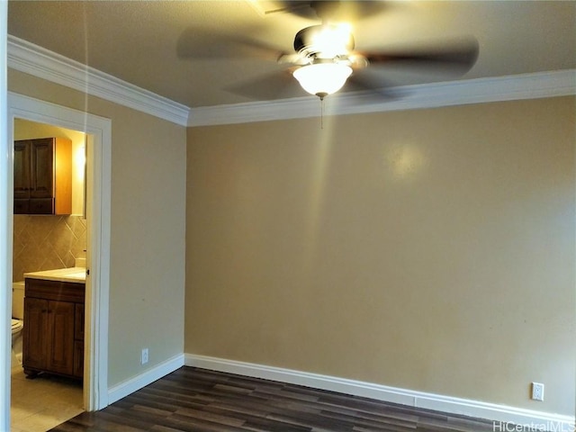 spare room with baseboards, dark wood-type flooring, ornamental molding, and a ceiling fan