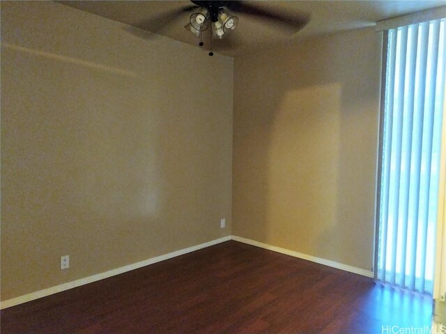 empty room with a ceiling fan, dark wood-style floors, and baseboards