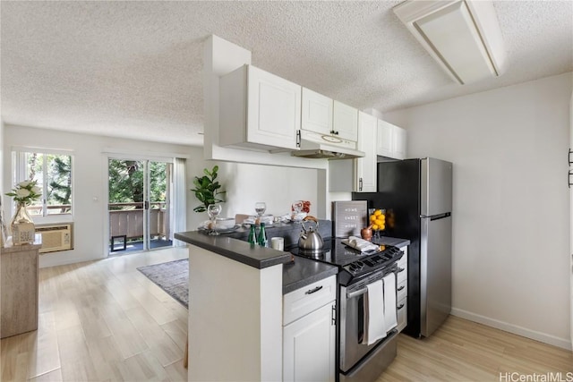 kitchen featuring dark countertops, open floor plan, a peninsula, stainless steel appliances, and white cabinetry