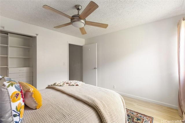 bedroom with light wood finished floors, a ceiling fan, baseboards, and a textured ceiling