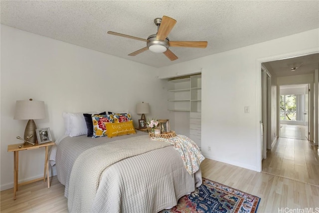 bedroom with a textured ceiling, light wood finished floors, a ceiling fan, and baseboards