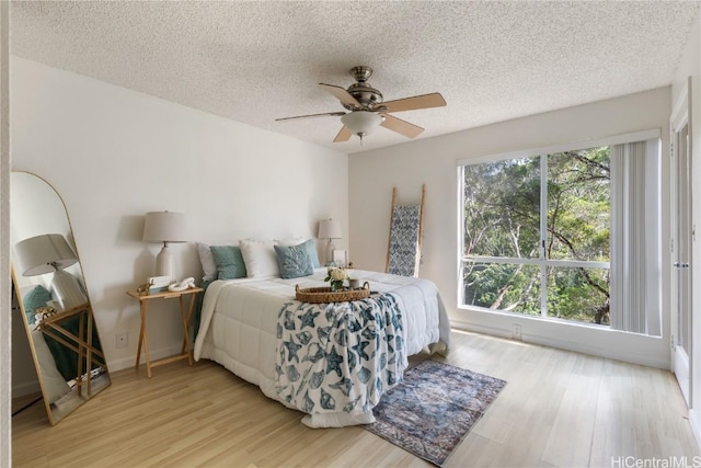 bedroom with light wood-style floors, ceiling fan, and a textured ceiling