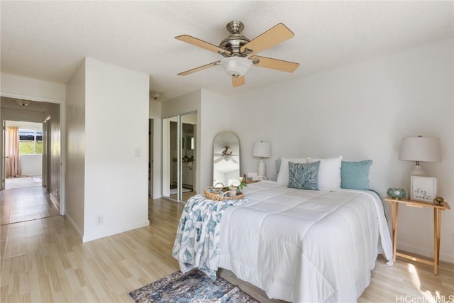 bedroom featuring a textured ceiling, a ceiling fan, baseboards, a closet, and light wood-type flooring