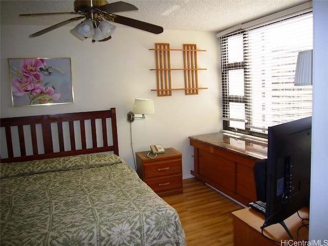 bedroom with ceiling fan, a textured ceiling, and wood finished floors