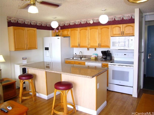 kitchen featuring white appliances, a sink, dark wood finished floors, a center island, and a kitchen bar