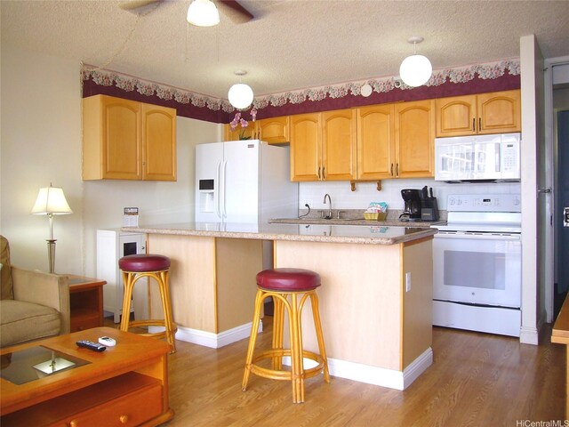 201 Ohua Ave Unit 2112Mauka, Honolulu, HI 96815 - kitchen with white appliances, wood finished floors, a kitchen bar, light countertops, and a textured ceiling