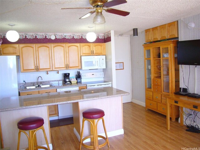 201 Ohua Ave Unit 2112Mauka, Honolulu, HI 96815 - kitchen featuring white appliances, a sink, light wood-style floors, a kitchen bar, and a textured ceiling