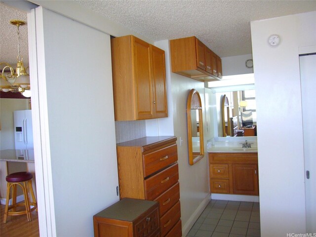 201 Ohua Ave Unit 2112Mauka, Honolulu, HI 96815 - kitchen featuring a sink, brown cabinets, a textured ceiling, light tile patterned floors, and a chandelier