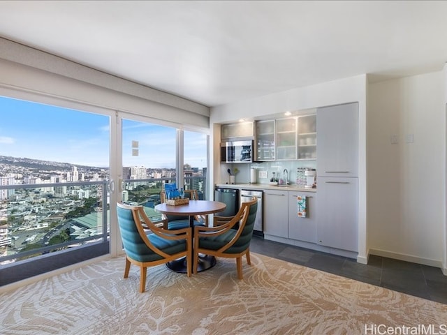 tiled dining area featuring indoor wet bar, a city view, a sink, and baseboards