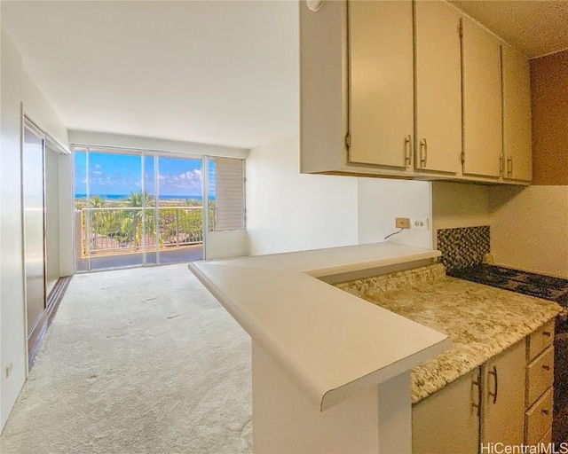 kitchen with a peninsula, floor to ceiling windows, light countertops, and light colored carpet