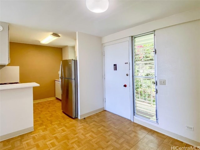 kitchen featuring freestanding refrigerator, white cabinetry, and baseboards