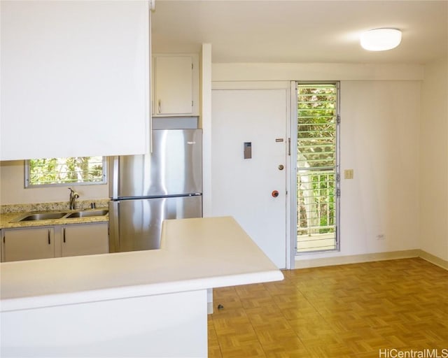 kitchen with a wealth of natural light, light countertops, a sink, and freestanding refrigerator