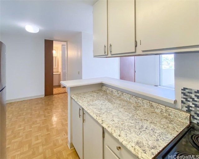 kitchen with baseboards, light stone counters, and white cabinets