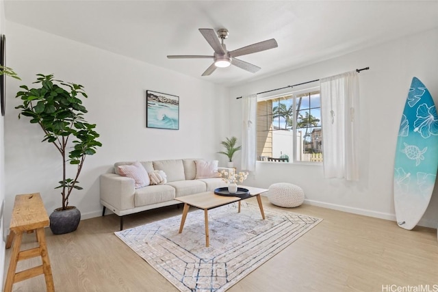 living room featuring light wood finished floors, ceiling fan, and baseboards