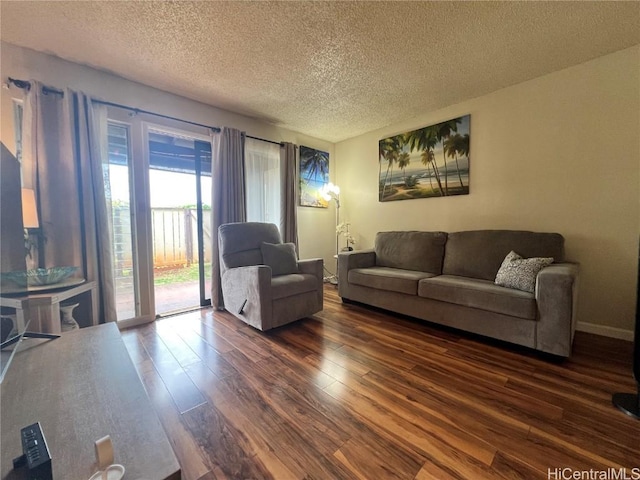 living area featuring dark wood finished floors, a textured ceiling, and baseboards