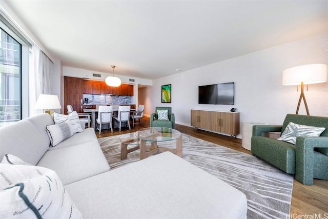 living area with wood finished floors, visible vents, and baseboards