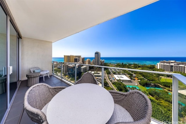 balcony featuring outdoor dining space, a water view, and a city view