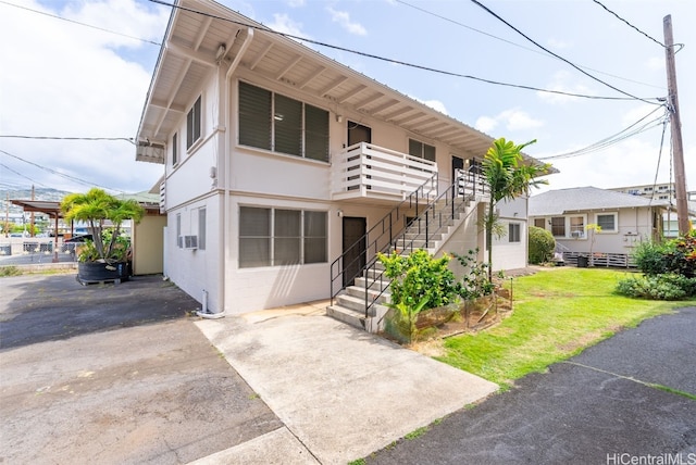 view of front of house featuring stairs, a front lawn, concrete block siding, and stucco siding